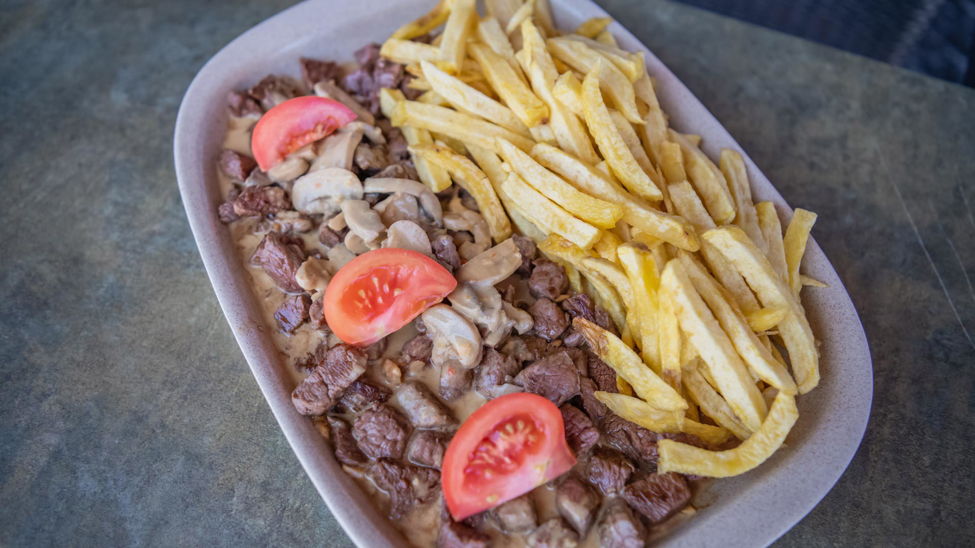 Plato con carne picada, patatas fritas y tomate.