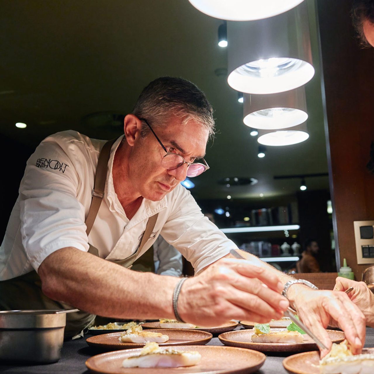 Chef presentando un plato contemporáneo de pescado inspirado en la gastronomía de la isla de Madeira.