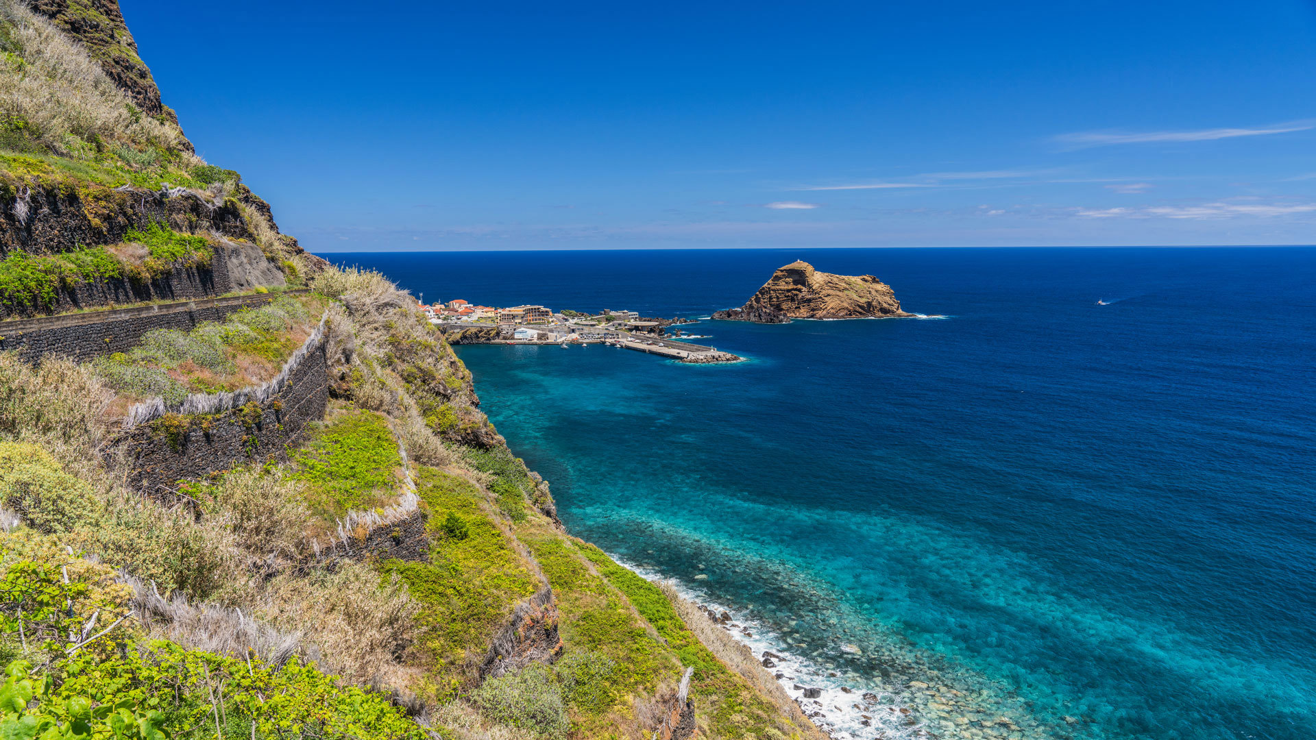 Green slope by the sea with rock formation in Madeira’s landscape.